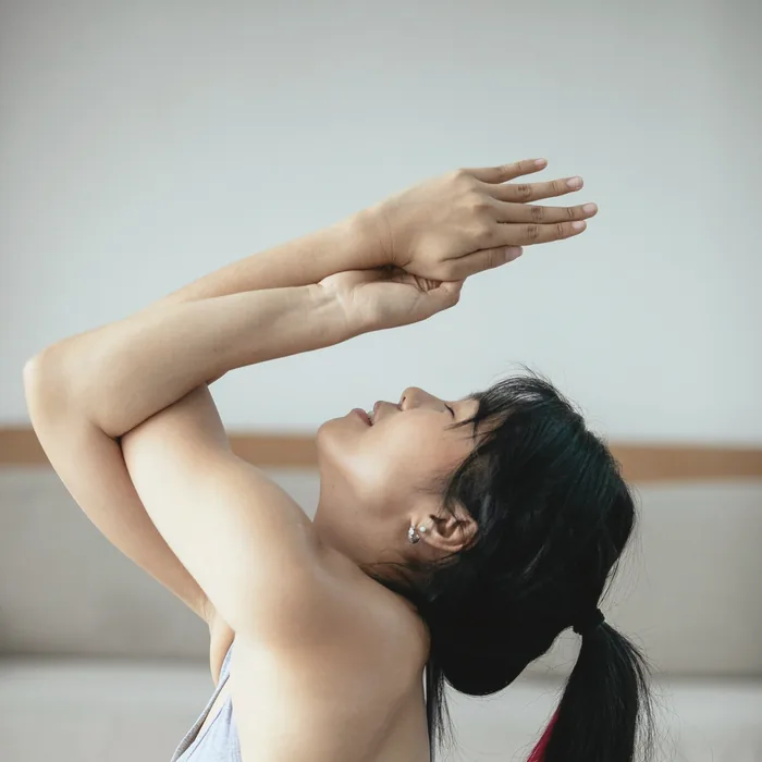 腕を上げて目を閉じる女性