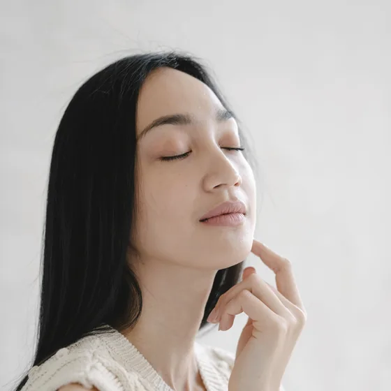 目を閉じて光を受ける女性の顔