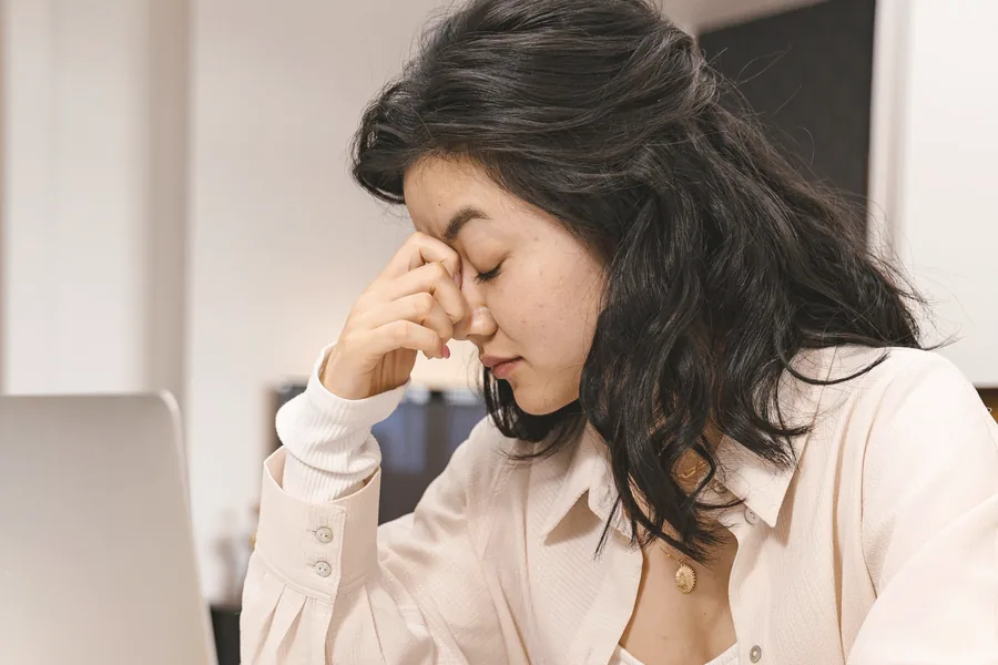 机に向かったまま、こめかみを押さえる女性