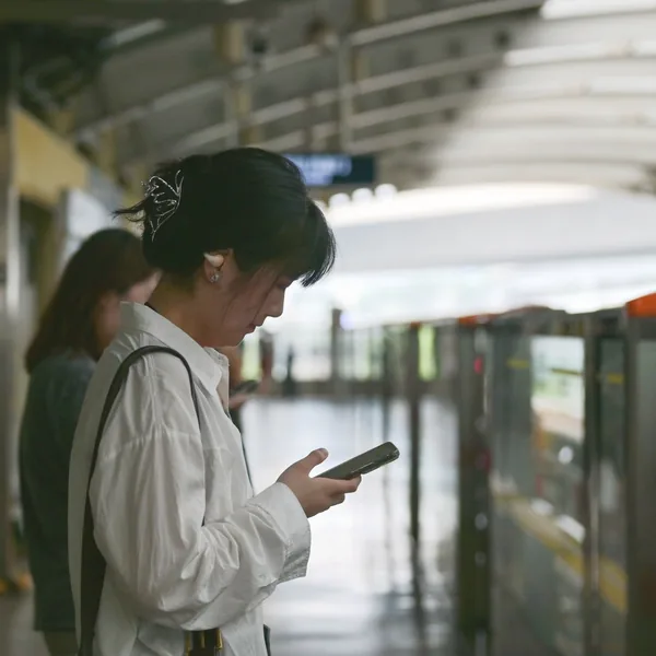 駅のホームでスマホを見る女性