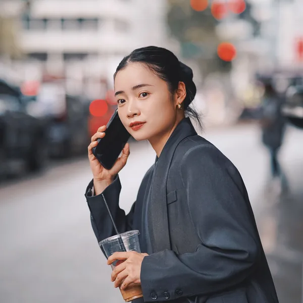 仕事帰り、コートでコーヒーと電話を持つ女性