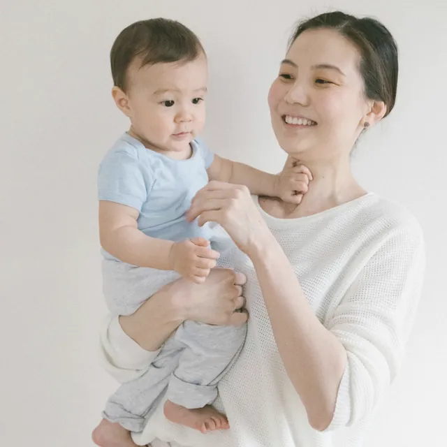 白いニットで赤ちゃんを抱っこする女性