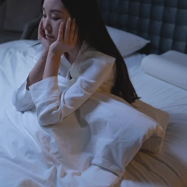 夜、ベッドの上で頬づえをつく女性