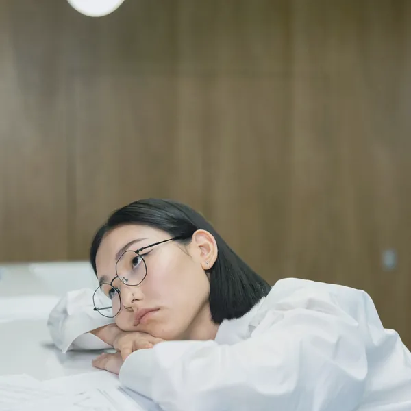 机に頭をのせて休む女性