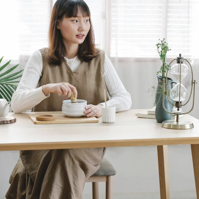 窓辺の机でお茶の用意をする女性