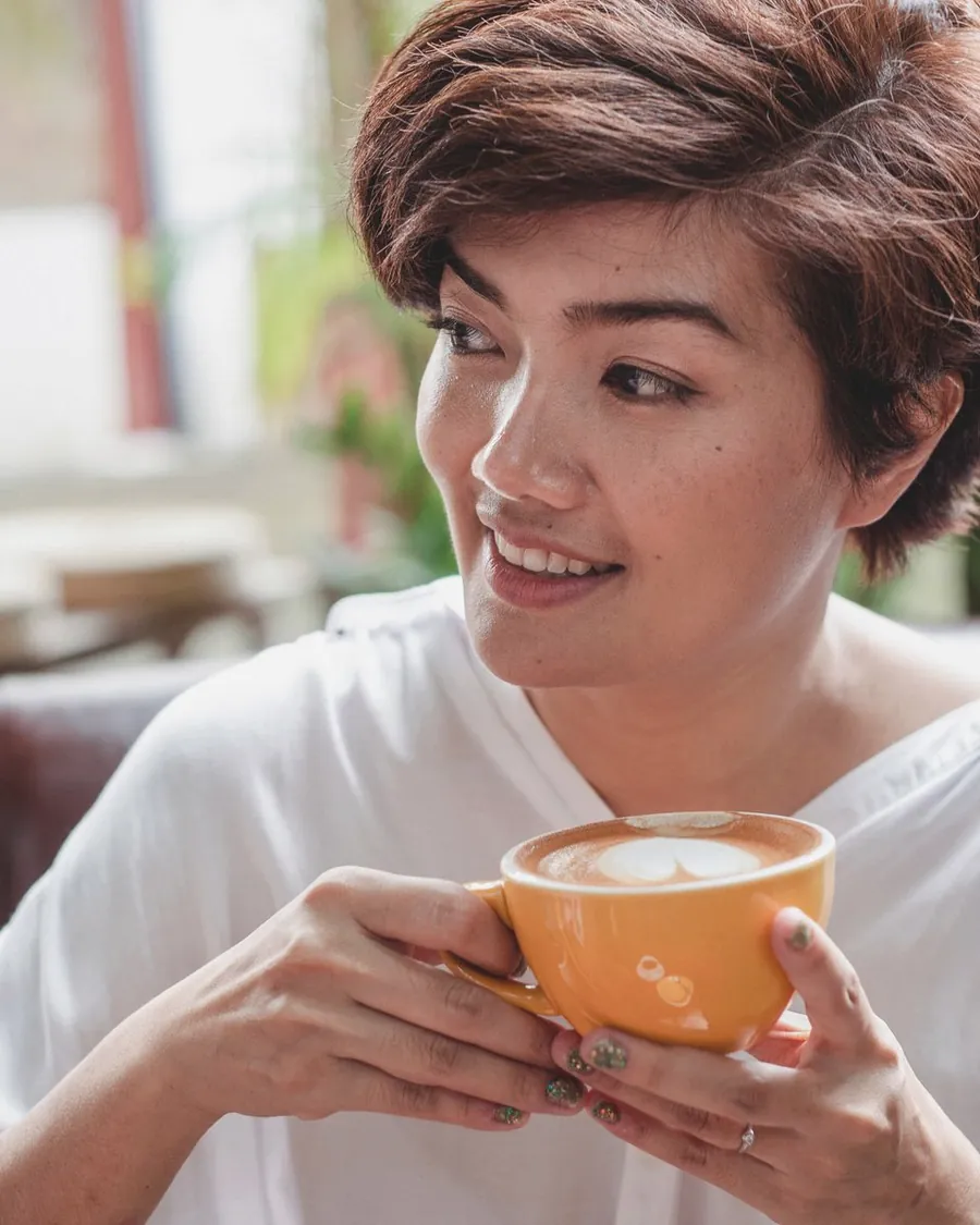 白いシャツでカップを持ち、笑顔を見せる講師